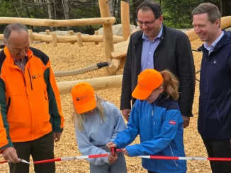 Zwei Kinder schneiden mit einer Schere das Absperrband zur Eröffnung des Spielplatzes durch. Links daneben steht Winfried Pfahler, dahinter Martin Schöffel, rechts Florian Wiedemann