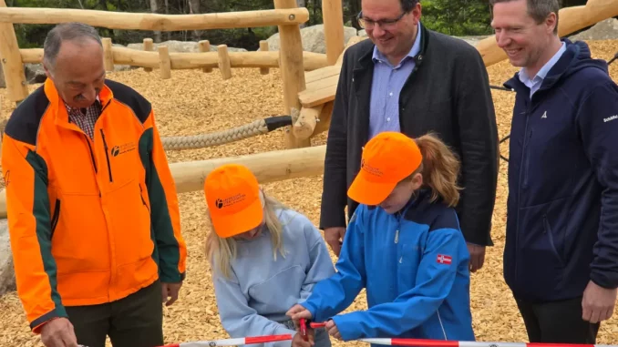 Zwei Kinder schneiden mit einer Schere das Absperrband zur Eröffnung des Spielplatzes durch. Links daneben steht Winfried Pfahler, dahinter Martin Schöffel, rechts Florian Wiedemann